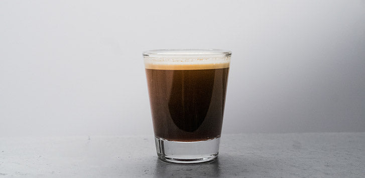 a shot of blonde espresso in a clear shot glass