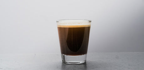 a shot of blonde espresso in a clear shot glass